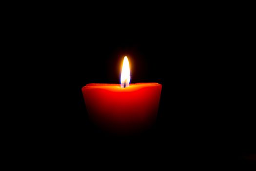 Closeup of burning candle isolated on black background.