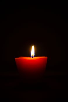 Closeup of burning candle isolated on black background.