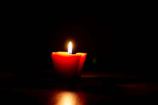 Closeup of burning candle isolated on black background.