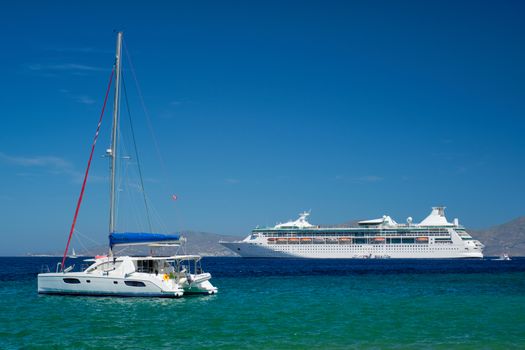 Catamaran yacht and cruise liner is Aegean sea on beautiful summer day. Chora, Mykonos island, Greece