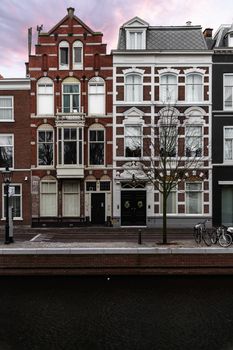 Flemish architecture style building dating from 1875 as stated on the facade and in front a calm canal water at Amsterdam during the sunset time