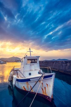 Old fishing boat in port of Naousa on sunset with dramatic sky. Paros lsland, Greece