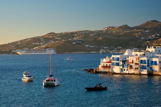 Sunset in Mykonos island, Greece with yachts in the harbor and colorful waterfront houses of Little Venice romantic spot on sunset and cruise ship. Mykonos townd, Greece