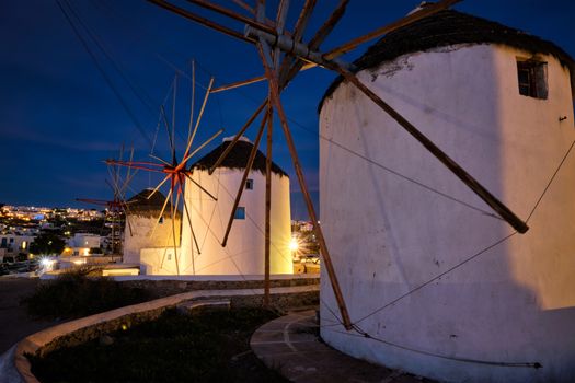 Scenic view of famous Mykonos Chora town windmills. Traditional greek windmills on Mykonos island illuminated in the evening, Cyclades, Greece. Walking with steadycam.