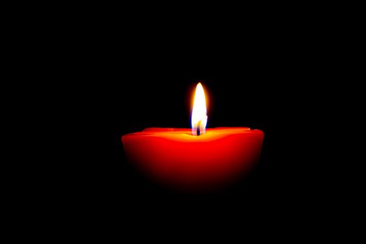 Closeup of burning candle isolated on black background.