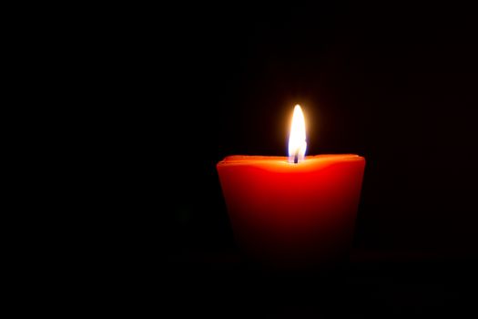 Closeup of burning candle isolated on black background.