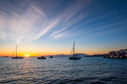 Sunset in Mykonos island, Greece with yachts in the harbor and colorful waterfront houses of Little Venice romantic spot on sunset and cruise ship. Mykonos townd, Greece