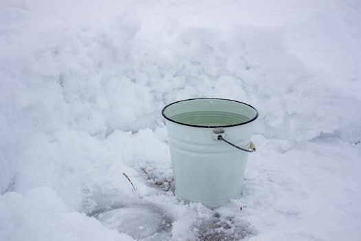 Bucket of water in the cold on the white snow