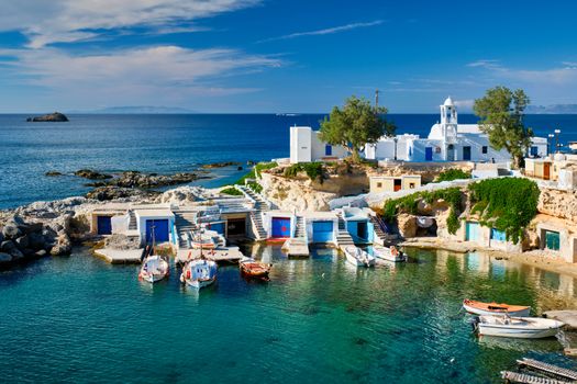 Typical Greece scenic island view - small harbor with fishing boats in crystal clear turquoise water, traditional white houses church. Mandrakia village, Milos island, Greece.