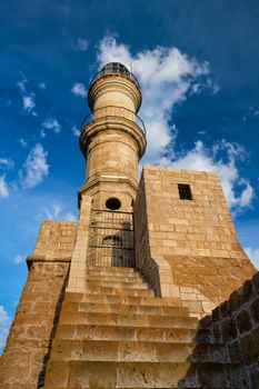 Lighthouse in old port of Chania against the blue sky with clouds, Crete island, Greece