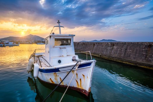 Old fishing boat in port of Naousa on sunset with dramatic sky. Paros lsland, Greece