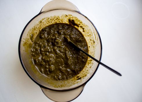 Mixing henna with a wooden spoon in a bowl for hair application of natural color like Indian henna mix