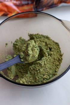 Mixing henna with a wooden spoon in a bowl for hair application of natural color like Indian henna mix