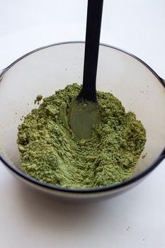 Mixing henna with a wooden spoon in a bowl for hair application of natural color like Indian henna mix