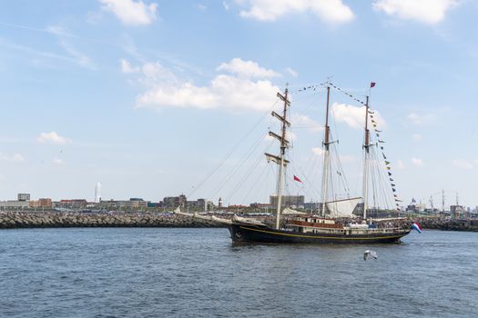 Antique tall ship, vessel leaving the harbor of The Hague, Scheveningen under a sunny and blue sky