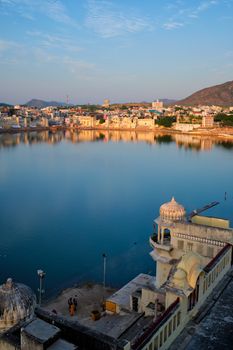 View of famous indian hinduism pilgrimage town sacred holy hindu religious city Pushkar amongst hills with Brahma mandir temple, lake and traditional Pushkar ghats at dusk sunset. Rajasthan, India