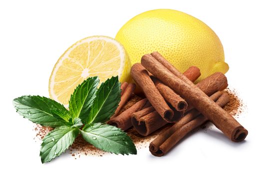 Whole and a half of lemon next to pile of cinnamon sticks, mint leaves and ground cinnamon. Clipping paths, shadow separated