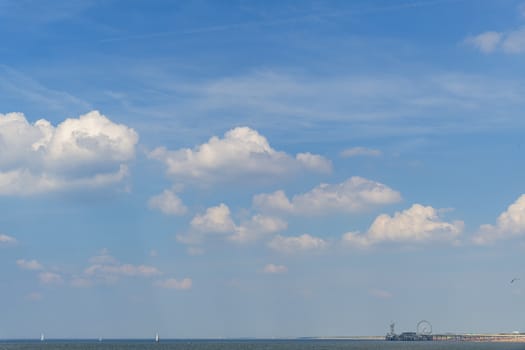 View of the beginning of the cumulonimbus clouds during the warm and wet weather with thick fog at the horizon and the sea side full of tall ships, Scheveningen, Netherlands