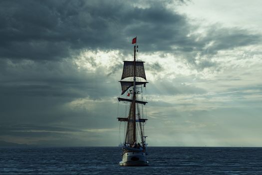 Antique tall ship, vessel leaving the harbor of The Hague, Scheveningen under a warm sunset and golden sky