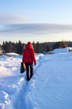 A girl in a red jacket walks through snowdrifts in Siberia, Russia