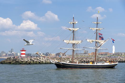 A seagull flying beside an antique tall ship, vessel leaving the harbor of The Hague, Scheveningen under a warm sunset and golden sky