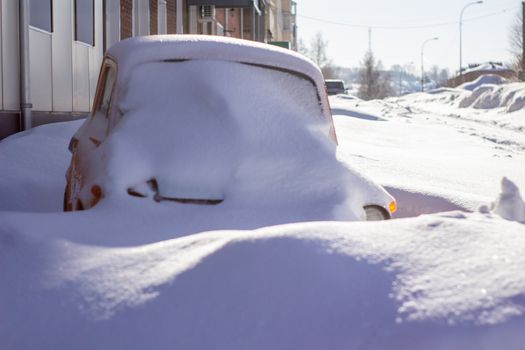 vehicles covered with snow in the winter blizzard in the parking lot.