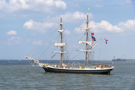 Antique tall ship, vessel leaving the harbor of The Hague, Scheveningen under a sunny and blue sky