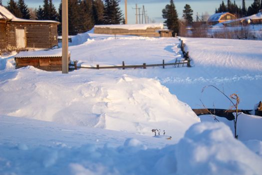 Wooden houses and fences covered with snow in Siberia, Russia