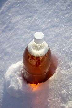 Plastic beer bottle in the snow in winter in nature, beer background