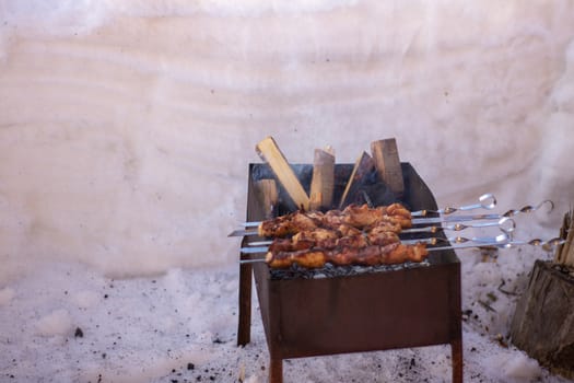 Cooking meat on the fire. Shish kebab on the grill. The grill is lit outside in winter. Fry shish kebabs on the grill