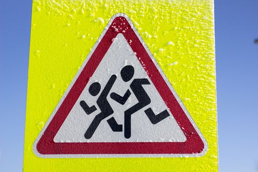 Pedestrian crossing sign on a yellow background. On a Sunny winter day