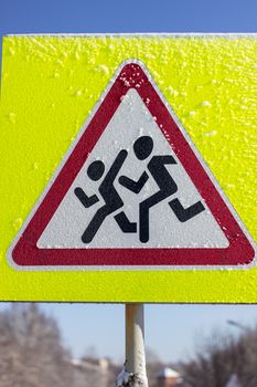 Pedestrian crossing sign on a yellow background. On a Sunny winter day