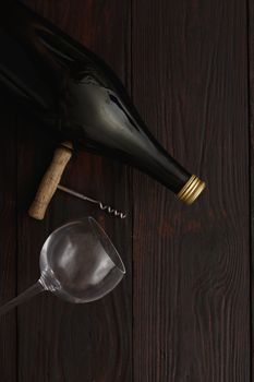 Bottle of red wine next to to empty glass with corkscrew on wooden table. Flat lay, above view, copy space,Chiaroscuro styled