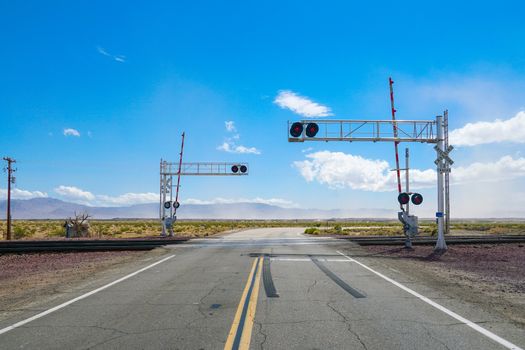 Railroad crossing gates on a road in the Mojave Desert in the Southwestern United States. California.