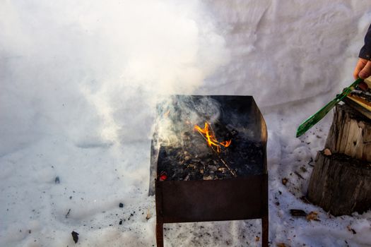 The grill is lit outside in winter. Fry kebabs