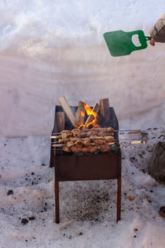 Cooking meat on the fire. Shish kebab on the grill. The grill is lit outside in winter. Fry shish kebabs on the grill