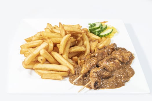 Chicken skewers served with a tasty peanut sauce and French fries