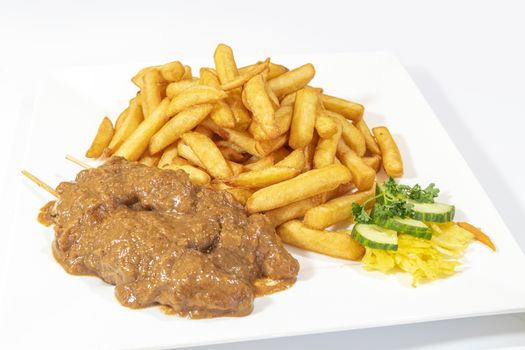 Chicken skewers served with a tasty peanut sauce and French fries