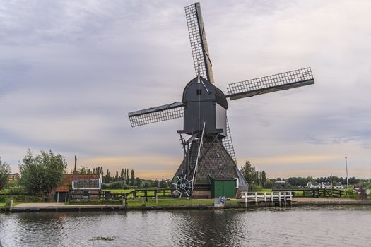 Majestic windmill reflected on the calm canal water during the bleu hour sunset in Alblasserdam city, Netherlands