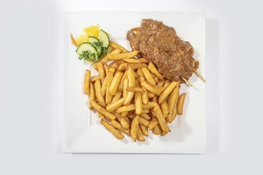 Chicken skewers served with a tasty peanut sauce and French fries