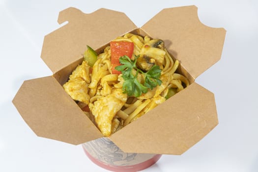 Box of stir fried chicken curry noodle served in a paper box for take away
