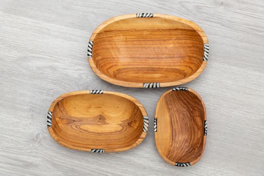 Rounded and rectangular wooden bowls for appetizers and fruits display against a laminated wooden background