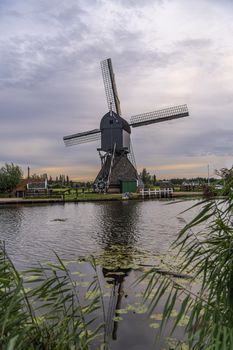 Majestic windmill reflected on the calm canal water during the bleu hour sunset in Alblasserdam city, Netherlands