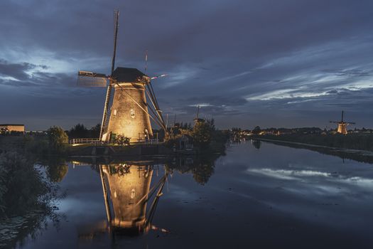 Illuminated windmill reflected on the calm canal water during the bleu hour sunset in Alblasserdam city, Netherlands
