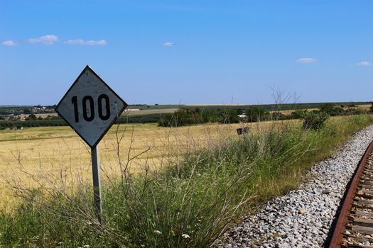Sign with the number 100 next to the old railway. Railway in Beja, Portugal.