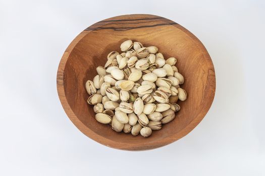 Chestnuts and pistachios in wooden bol as appertiser with drinks against a white background