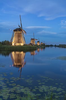 Illuminated windmill reflected on the calm canal water during the bleu hour sunset in Alblasserdam city, Netherlands