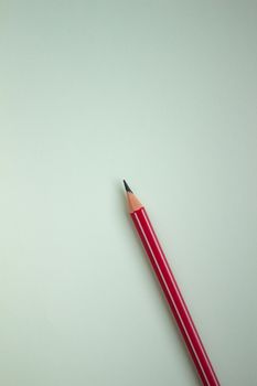 One red pencil on a light green background