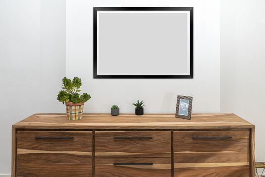 View of the white room with a drawer and empty frames against a white wall