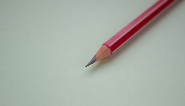 One red pencil on a light green background